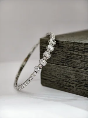 Silver stone kada bracelet featuring a row of sparkling white oval stones set with smaller round stones.