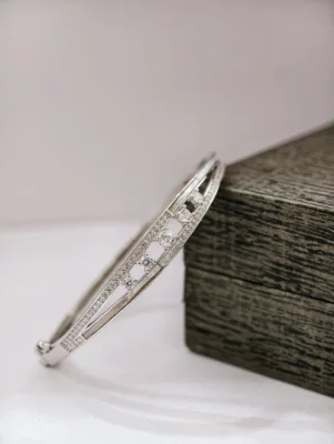 A silver stone kada bracelet featuring white stones set along double rows and scattered larger center stones.