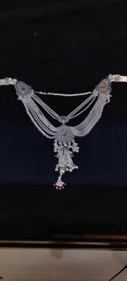 This multi-layered silver waist chain features intricate patterns, small ghungroos, and delicate stone detailing with gold polish accents.