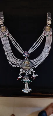Silver waist chain featuring multi layer links, colorful stones, detailed circular center motif, and hanging ghungroos.