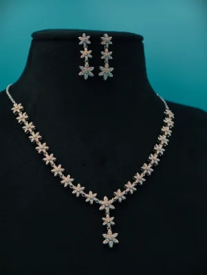Silver necklace and matching earrings featuring sparkling white stone floral motifs in a delicate drop pattern.