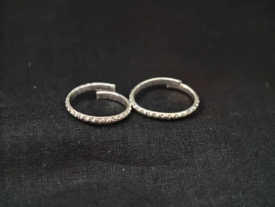 Pair of simple silver bichiya with textured patterns and adjustable open ends.