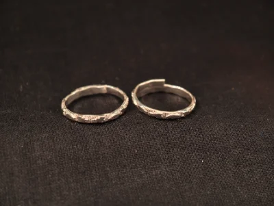 A pair of simple open silver toe rings with a textured geometric pattern.