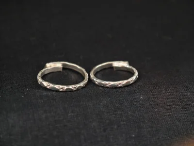 A pair of simple openable silver toe rings featuring a delicate textured pattern all around.
