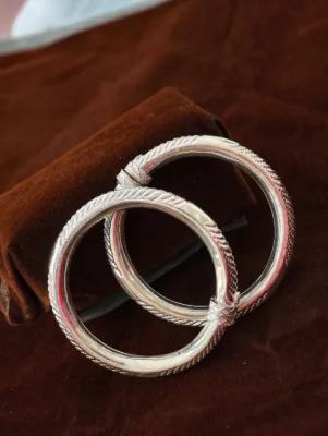 Silver hollow kada with textured patterns and polished finish.