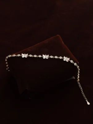 A silver bracelet featuring delicate butterfly motifs and small round white stones linked together in a charming chain pattern.