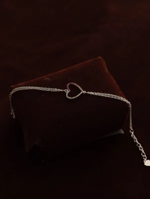 Delicate silver bracelet featuring a heart center studded with pink and white stones and thin chain links.
