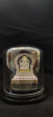 Silver murti of Ganesha seated on a throne, adorned with red and white stones and gold polish highlights.