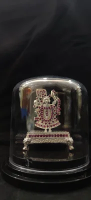 Heavy silver idol decorated with red stones standing on an ornate silver base.