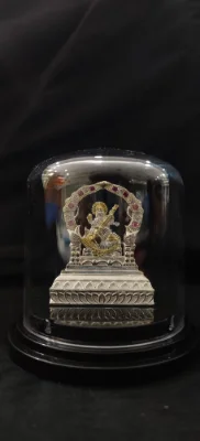 Heavy silver idol showing a seated figure with red and white stones under an ornate arch on a lotus base.