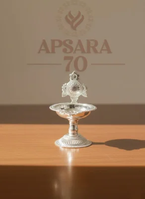 This decorative silver lamp features intricate embossed floral patterns, a shiny polished finish, and a traditional design.