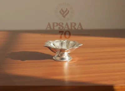 A shiny silver decorative lamp featuring a floral shape with fluted patterns on a round base.