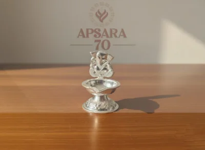 This decorative silver lamp features an embossed Ganesha idol and intricate patterned base.