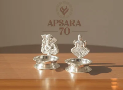 Glossy silver decorative lamp featuring embossed Lord Ganesha and Goddess Lakshmi figures on round bases.