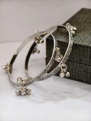 Silver oxidised kada bangles featuring intricate engraved floral patterns and hanging ghungroo bells.