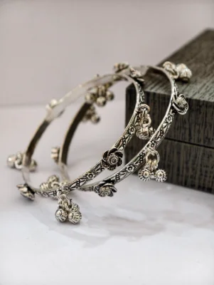 Silver oxidised ghungroo bangles featuring floral patterns and hanging bells.