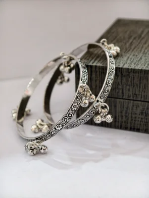 Silver oxidised bangles featuring floral patterns and dangling ghungroo charms.