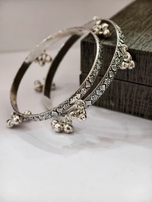 Silver oxidised bangles featuring intricate engraved patterns and dangling ghungroo charms along the edges.