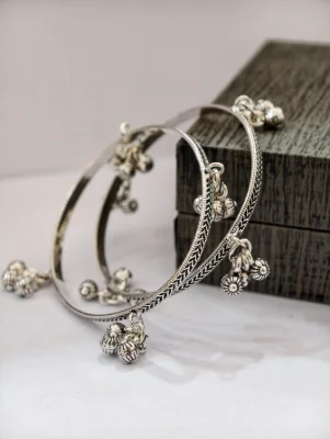 Silver oxidised ghungroo bangles featuring intricate engraved patterns and dangling metallic bells.