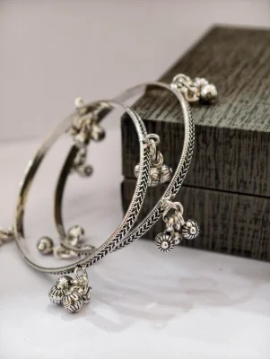 Silver oxidised bangles featuring intricate engraved patterns and hanging ghungroo bells.