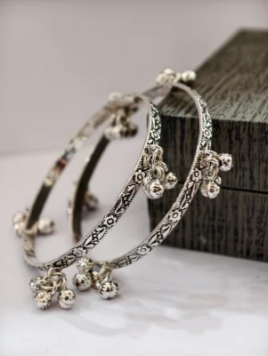 Silver oxidised bangles featuring floral patterns and hanging ghungroo bells.