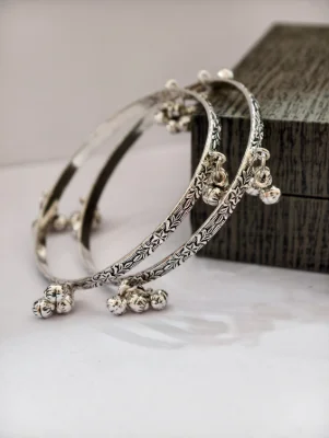 Silver oxidised ghungroo bangles featuring floral patterns and hanging little bells.