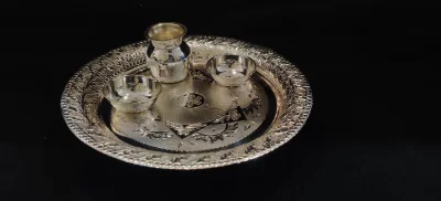 Glossy silver worship thali set featuring an engraved round plate, a small kalash, and two bowls.