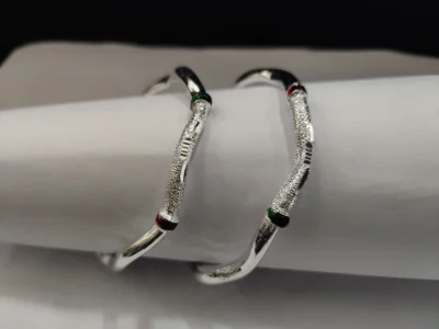 Glossy silver bangles featuring a textured center pattern with red and green accents.