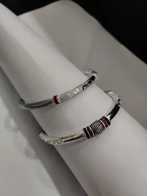 These are ethnic silver kadas featuring textured patterns, black polish, and red accents.