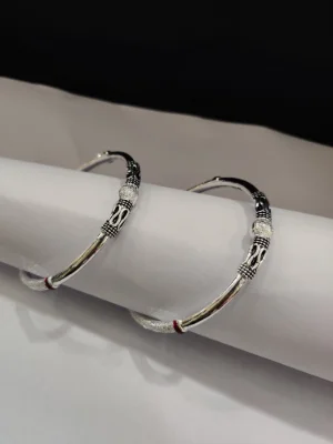 These round silver bangles feature textured patterns, shiny polished sections, and dark oxidised detailing.