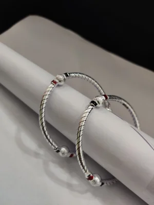 Silver bangles featuring a twisted pattern with textured round ends and black and red enamel details.