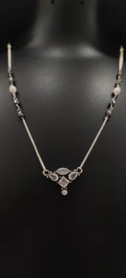 A delicate oxidised silver mangalsutra featuring a geometric pendant with white stones and black beaded chain details.