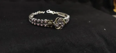 Oxidised silver bracelet featuring a floral centrepiece and double rows of pink stones with an antique finish.