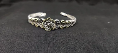 Oxidised silver bracelet featuring a floral centrepiece set with sparkling black stones and intricate metal patterns.