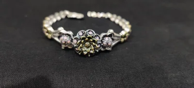 Oxidised silver bracelet featuring floral motifs with pink stones and linked chain work.