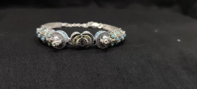 Oxidised silver bracelet featuring peacock motifs, intricate patterns, and blue stones.