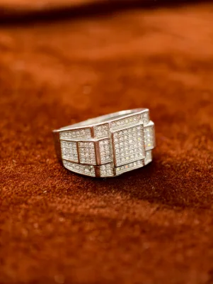 Silver male ring featuring a broad geometric design paved with tiny white stones.