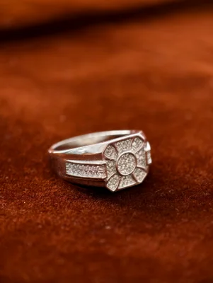 Silver male ring featuring a geometric pattern embedded with small white stones on the top and band.