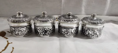 Four round silver soap dishes with dome lids feature detailed floral patterns and polished rims.