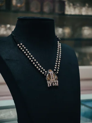 Oxidised silver mangalsutra featuring a double beaded black thread chain and a detailed pendant with colored stones.