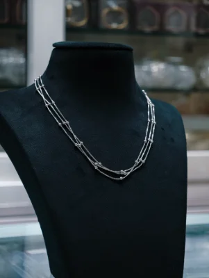 A triple layer silver beaded chain featuring fine textured strands and round metallic beads in a sleek finish.