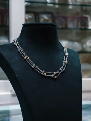 This is a silver multi-strand chain featuring alternating small silver and gold polished beads.