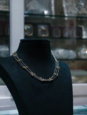 A delicate triple layer sterling silver chain featuring small silver and gold polished beads.