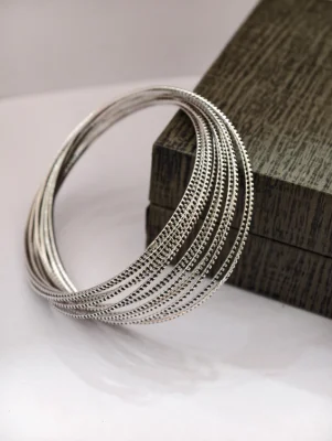 Set of round silver oxidised bangles with textured beaded patterns.