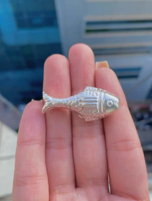 Polished silver yantra shaped like a fish with textured scales and a simple eye.