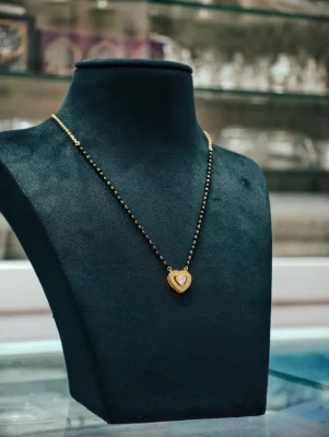 Silver mangalsutra with black beads, heart pendant set with small white stones and a central stone.