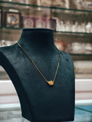 A delicate silver mangalsutra featuring a central locket and black beaded chain.