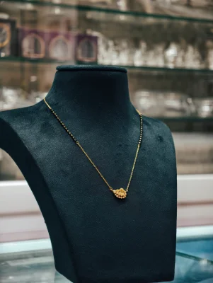 A delicate silver mangalsutra featuring a gold polished pendant with white stones and black beads along the chain.