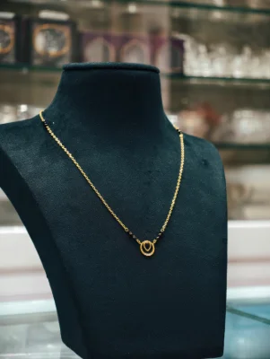Silver mangalsutra with black beads, delicate chain, and a circular pendant featuring a teardrop design.