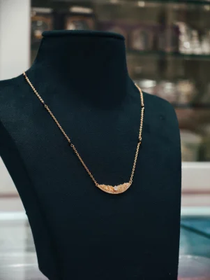 Silver mangalsutra with a curved pendant, small white stones, and black beads along the chain.